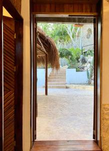 an open door to a patio with a straw roof at Xcabal Hotel boutique in Bacalar