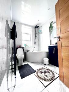 a bathroom with a tub and a toilet and a sink at Family and Private Home in Norbury