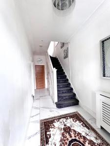a white hallway with stairs and a rug at Family and Private Home in Norbury