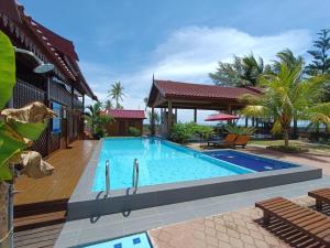 a swimming pool in front of a house at Bayu Beach Penarek in Kampung Penarik