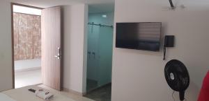 uma casa de banho com um chuveiro e uma televisão na parede em Aptahotel Guest House em San Gil