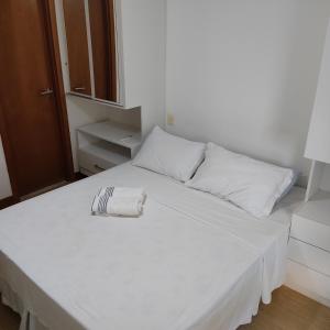 ein weißes Bett mit einem Handtuch darüber in der Unterkunft Apartamento Coração do Carnaval in Salvador