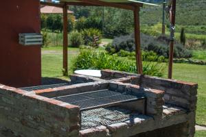 una hoguera de ladrillo con una parrilla en un patio en Cabañas Los Pioneros en Tandil