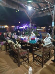 a group of people sitting around a wooden table at Bayu Beach Penarek in Kampung Penarik