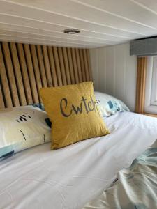 a bed with a yellow pillow with the word outreach on it at Cwtch Cader Shepherds Hut in Llanelltyd