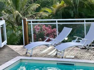 帕蒂博的住宿－VILLA JASMIN : EXCEPTIONNELLE !!，游泳池旁的甲板上摆放着两把椅子