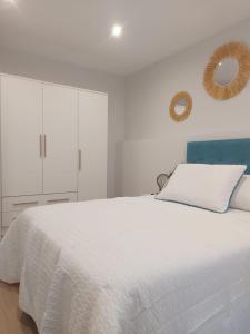 a white bedroom with a white bed and a mirror at Apartamento Silleda Confort in Silleda