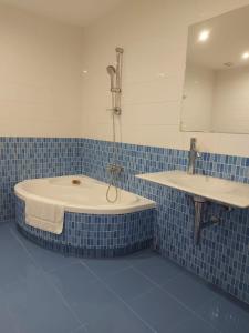 a blue tiled bathroom with a tub and a sink at Apartamento Silleda Confort in Silleda