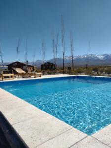 ein großer blauer Pool mit Bergen im Hintergrund in der Unterkunft cabañas de montaña in Uspallata