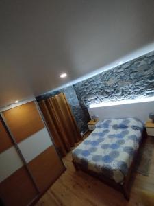um quarto com uma cama e uma parede de pedra em Casa do terno com piscina em Arco da Calheta