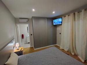 a bedroom with a bed and a flat screen tv at Casa do terno com piscina in Arco da Calheta