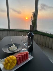 a table with a plate of fruit and a bottle of wine at Sea-front apartment Netanya in Netanya