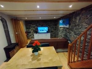 a living room with a table and a television at Casa do terno com piscina in Arco da Calheta