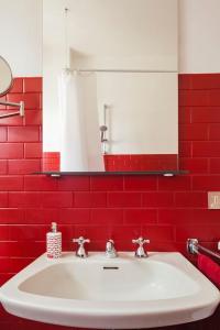 La salle de bains est pourvue d'un lavabo blanc et d'un mur rouge. dans l'établissement While apartment underground and bus station a/c, à Milan