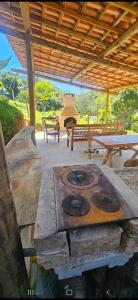 a wood stove in a pavilion with a picnic table and benches at Serra Mar à beira rio , rafting, suites, lofts, e Casas in Casimiro de Abreu