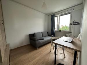 a living room with a couch and a table with a laptop at Rooms4Less in Gdańsk