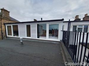 a extension to a house with whitewindows and a fence at Bridge Street Guest Rooms in Tranent