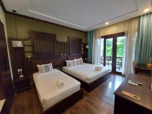 a hotel room with two beds and a desk at Sunrise Garden House - Luang Prabang in Luang Prabang