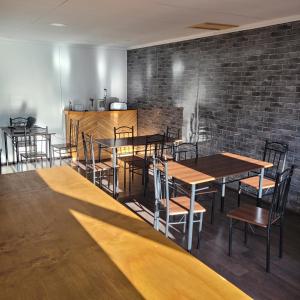 a restaurant with wooden tables and chairs and a brick wall at Hostal Casa Blanca in Puerto Natales