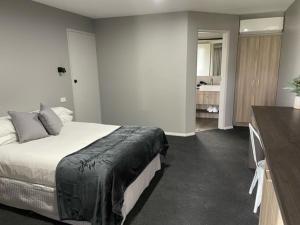 a bedroom with a bed and a dresser in a room at Murrumbateman Country Inn in Murrumbateman