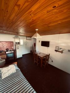 a room with a bed and a table and a kitchen at Cabañas Los Pioneros in Tandil