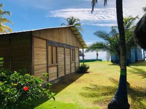 una pequeña casa de madera con palmeras frente al océano en HOSTAL CRUZ DEL MAR, en Capurganá