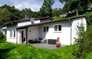 a white house with a patio in the yard at Eifel Cottage Biersdorf am See in Biersdorf