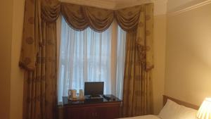 ein Schlafzimmer mit einem Bett und einem Fenster mit einem Monitor in der Unterkunft Hotel Sergul in London