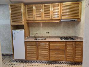 a kitchen with wooden cabinets and a sink and a refrigerator at Mirleft View in Mirleft