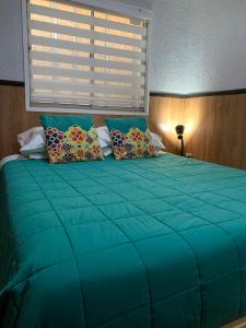 uma grande cama verde com almofadas e uma janela em La Quebrada de Pinomar em El Quisco
