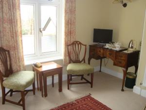 a living room with a desk and a tv and a window at Stoneborough House B&B in Budleigh Salterton