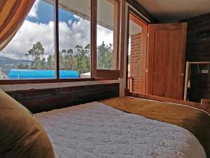a bedroom with a large bed with a large window at Lagoon Hotel Chugchilan in Chugchilán