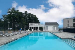 uma piscina com cadeiras e um edifício em Cedar Lodge Condo, Unit 205 em Laconia