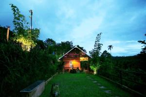 una pequeña casa en un patio por la noche en Agronest Farm & Resort By Teal Luxury Stay, en Wayanad