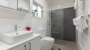 a white bathroom with a sink and a toilet at 99 Reef Resort Port Douglas in Port Douglas