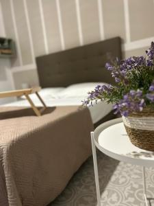 ein Schlafzimmer mit einem Bett und einem Tisch mit lila Blumen in der Unterkunft Casa la cava in Taranto