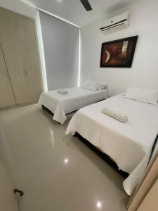 Duas camas num quarto com paredes brancas em Apartamento nuevo con vista al mar em Coveñas