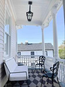 um alpendre com um sofá branco e 2 cadeiras em The Juliette - Luxury Historic Residence em Charleston