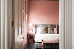 a bedroom with a bed with a pink wall at The Juliette - Luxury Historic Residence in Charleston