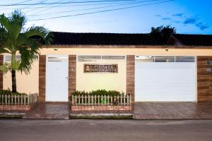 a building with two white garage doors and a palm tree at Pousada Muiraquitã Parintins in Parintins