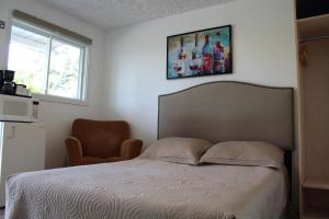 a bedroom with a bed and a chair and a window at Le Marigot in Vaudreuil-Dorion