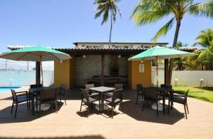 a patio with tables and chairs and umbrellas at Porto de Galinhas - Apartamento Flat Sea Residence 304 in Porto De Galinhas