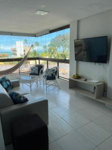 a living room with a television and a couch and chairs at Porto de Galinhas - Apartamento Flat Sea Residence 304 in Porto De Galinhas