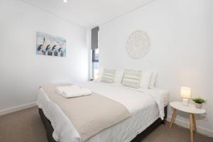 Un dormitorio blanco con una cama y una mesa. en Obsidian Blue Huskisson, en Huskisson