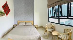 a bedroom with a bed and two chairs and a window at Tùng Dương Homestay in Cao Bằng