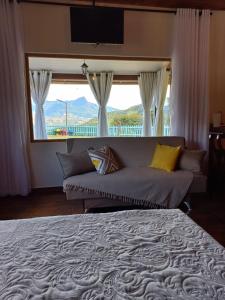 a bedroom with a large bed and a large window at Chalé Mirante Da Guapiara in Aiuruoca