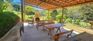 a patio with benches and a table and a fireplace at Serra Mar à beira rio , rafting, suites, lofts, e Casas in Casimiro de Abreu