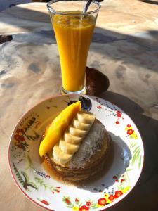 une assiette de crêpes avec une banane et un verre de jus d'orange dans l'établissement SAJA Cottage, Gili Meno, à Gili Meno