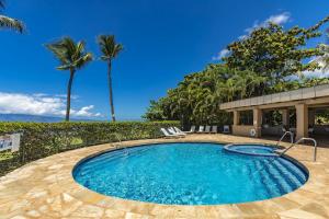 een zwembad met palmbomen en een gebouw bij Paki Maui #103 condo in Kahana