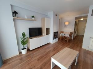 a living room with a flat screen tv and a table at Margas Golf Apartment 2 in Sabiñánigo